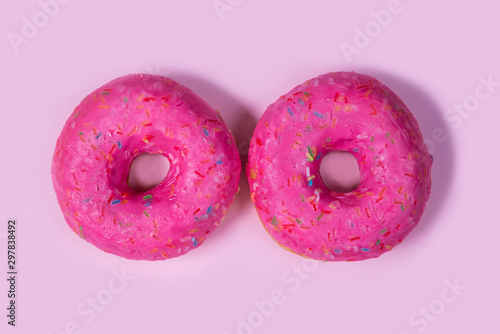 Two sweet pink donuts isolated on background. Bright tasty bun. Minimal summer concept. Flat lay. The concept of unhealthy eating and weight gain. Harmful fast food