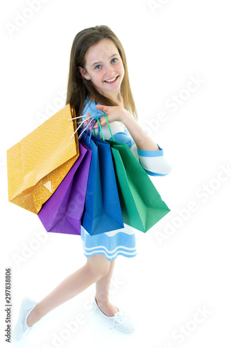 Teenager girl shopping in a store with large paper bags.