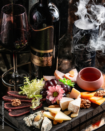 Fotografie cheese plate with gouda, cheddar, goat and blue cheese, dried fruits and flowers