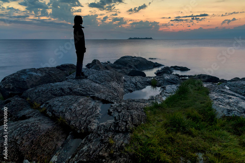A woman walks along the rocks on the coast in Colonia  Uruguay