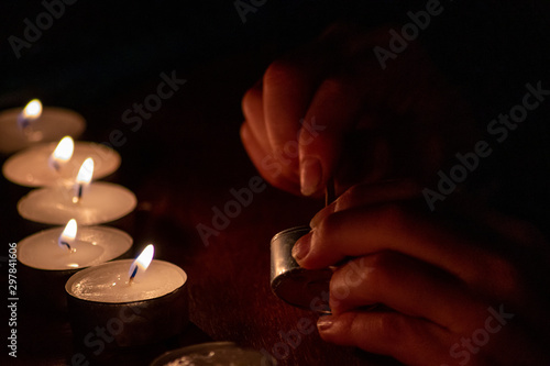 Kinderhand spielt mit dem Feuer mit Kerzen und Kerzenschein in der Dunkelheit der Adventszeit mit Vorfreude auf Weihnachten und Adventskranz