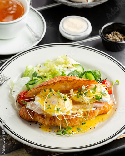 croissant benedict salmon with poched egg, hollandaise sauce, served with fresh salad