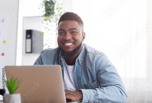 Portrait of smiling african employee at workplace in modern office