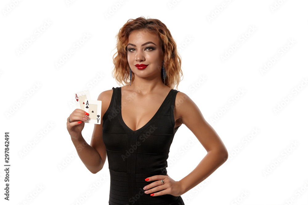 Ginger girl wearing a black dress is posing holding two playing cards in her hands standing isolated on white background. Casino, poker. Close-up.