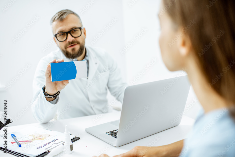 Senior doctor offering some medicine for a young patient, holding box with blank space to copy paste in the medical office Senior doctor offering some medicine for a young patient, holding box with blank space to copy paste in the medical office