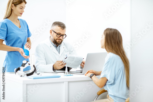 Young patient at an appointment with otolaryngologists, sitting during the consultation in the bright ENT office interior