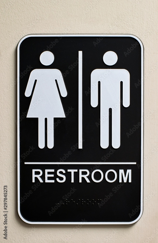 Vertical restroom sign on a wall for a unisex bathroom with male and female icons, braille at the bottom and no handicap icon. Vertical restroom sign on a wall for a unisex bathroom with male and female icons, braille at the bottom and no handicap icon.