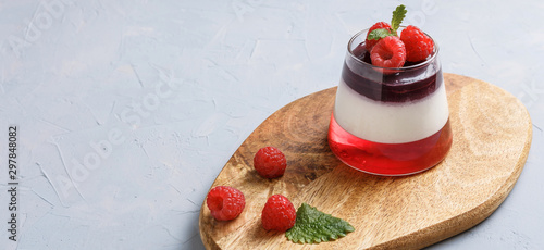 Berry jelly topping with raspberries in a glass cup on a wood stand. Top view.