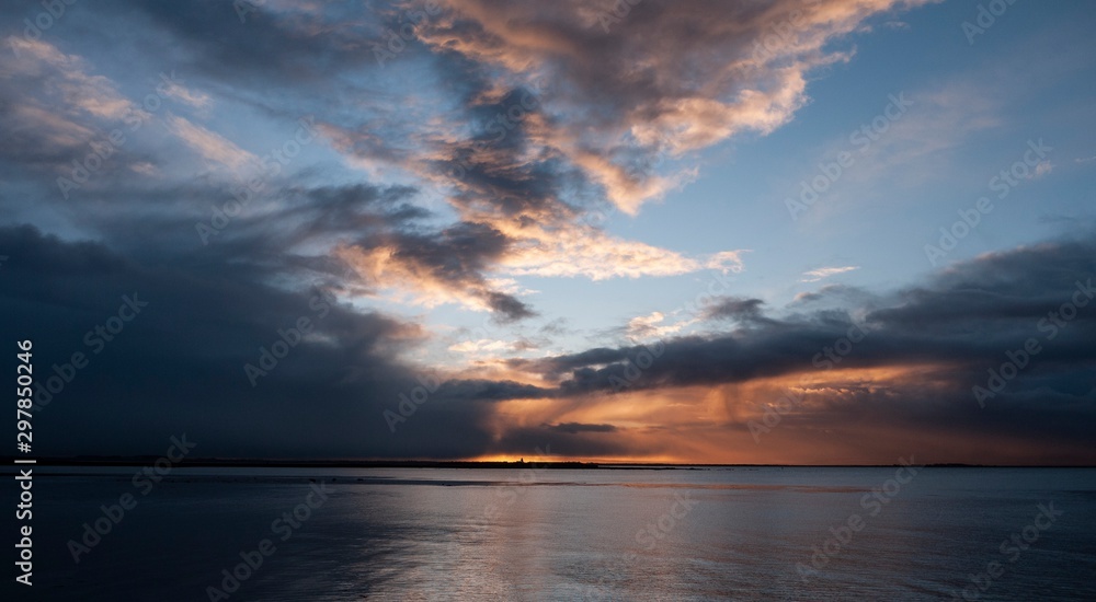 Stunningly beautiful sunrise, taken on a cloudy morning from Salthill beach near Galway, Ireland. Showing the calm water of Galway Bay and Mutton Island in the distance.