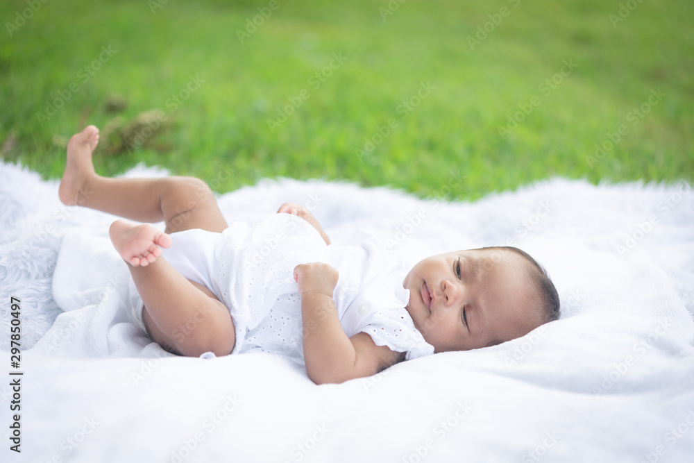 Portrait of cute new born baby girl lying on the white cloth mattress in the lawn Portrait of cute new born baby girl lying on the white cloth mattress in the lawn