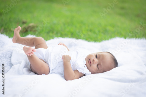 Portrait of cute new born baby girl lying on the white cloth mattress in the lawn