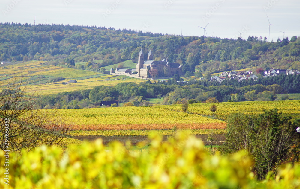 Ein Blick von der Ferne auf die Abtei St. Hildegard mit Windrädern im Hintergrund und Feldern und Reben im Herbst in Rüdesheim im Rheingau am Rhein in Hessen Deutschland