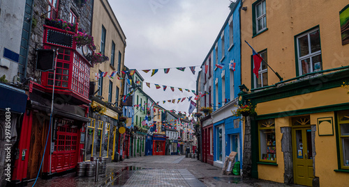 View of the main high street in Galway City with the brightly painted buildings and cobblestone streets on a cloudy day © Michaella
