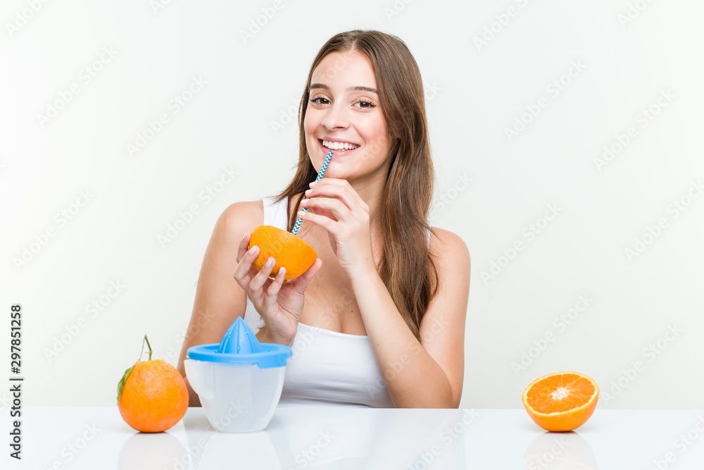 Young caucasian woman drinking an orange with a straw. Healthy life concept Young caucasian woman drinking an orange with a straw. Healthy life concept