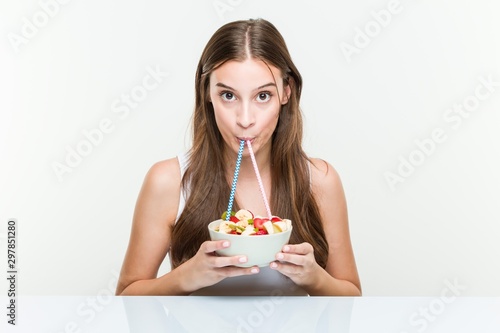 Young caucasian woman drinking a fruit bowl with a straw. Healthy life concept.