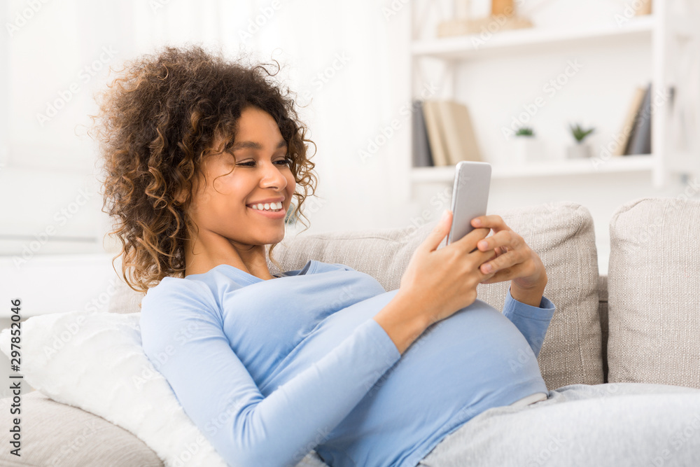Happy pregnant woman surfing the net on smartphone Happy pregnant woman surfing the net on smartphone