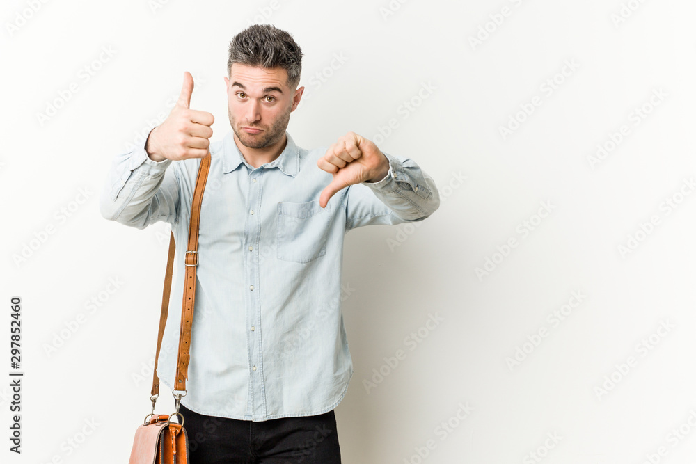 Fototapeta premium Young handsome business man showing thumbs up and thumbs down, difficult choose concept