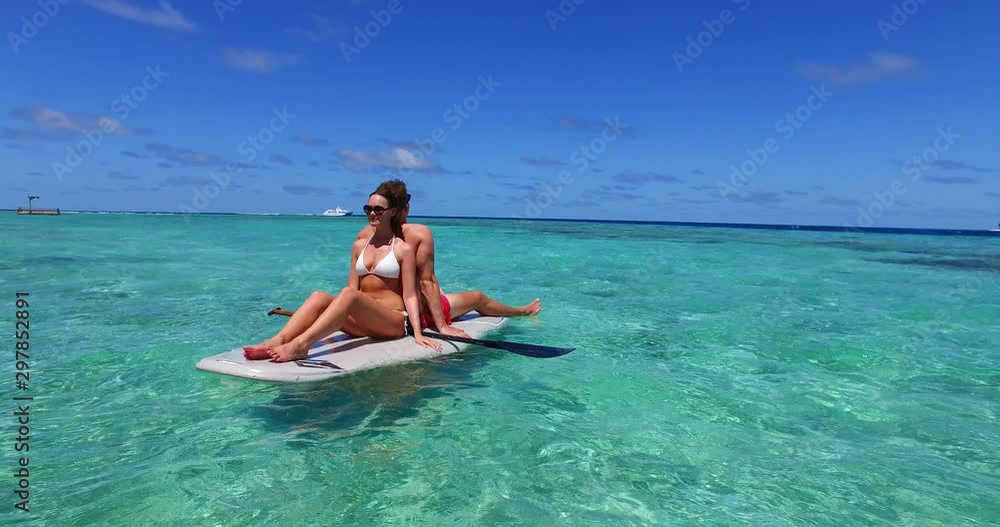 Couple resting on each other's backs over a swimming board in emerald waters of Aleutian Islands Couple resting on each other's backs over a swimming board in emerald waters of Aleutian Islands