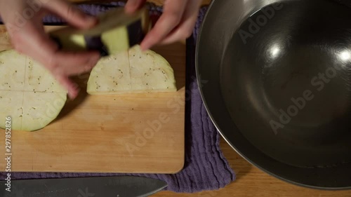 a Japanese female chef putting cut KAMONASU (Japanese round aubergine) in water at her kitchen table, Tokyo, Japan. July 2019. Camera fixed, close up, bird's eye view photo