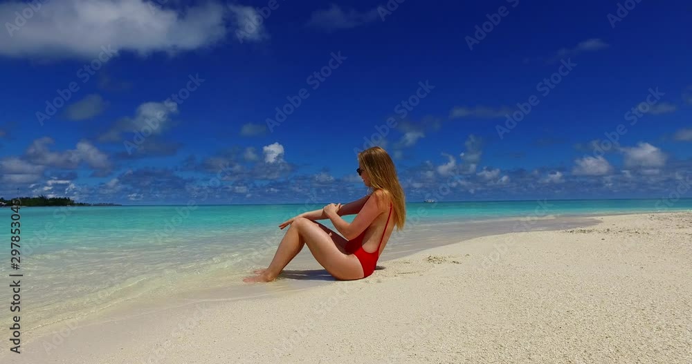 Sideview of a blond girl sitting on the white beach, watching ocean on a cloudy summer day in Philippines Sideview of a blond girl sitting on the white beach, watching ocean on a cloudy summer day in Philippines