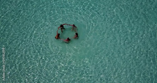 Top view of group of five young people handling hands on shallow turquoise water in Pulau Biola, Singapore photo