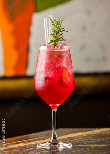 strawberry cocktail in glass with rosemary and straws