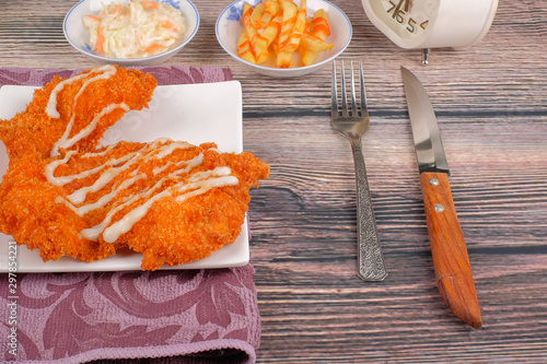 Chicken chop in white plate , coleslaw and french fries on wood background