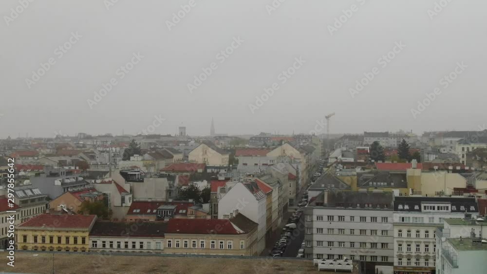 Aerial view from left to right. Flying above the city of Vienna, Austria. View of the skyline with houses and building in a foggy day with white clouds. Aerial view from left to right. Flying above the city of Vienna, Austria. View of the skyline with houses and building in a foggy day with white clouds.