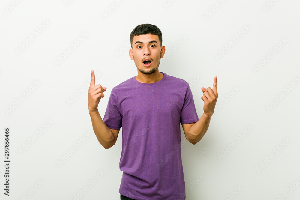 Young hispanic man pointing upside with opened mouth. Young hispanic man pointing upside with opened mouth.