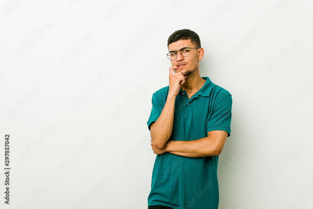 Young hispanic man relaxed thinking about something looking at a copy space. Young hispanic man relaxed thinking about something looking at a copy space.
