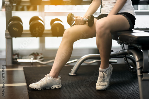 Happy beautiful asian woman smiling and lifting dumbbells cheerful in sports fitness gym , excersie and healthcare concept