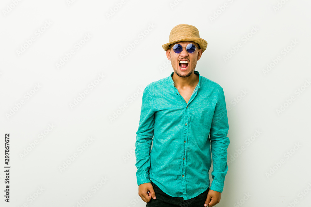 Young hispanic man wearing a summer clothes screaming very angry and aggressive. Young hispanic man wearing a summer clothes screaming very angry and aggressive.