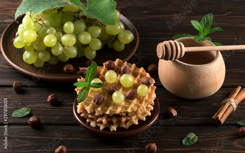 waffles with grapes and honey on a wooden background