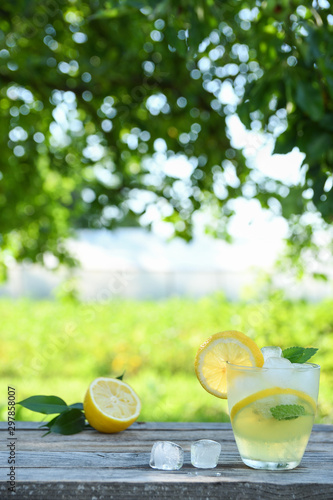 Glasses of lemon juice on a wooden table, summer set, outdoor greed blured background,boke.Water detox