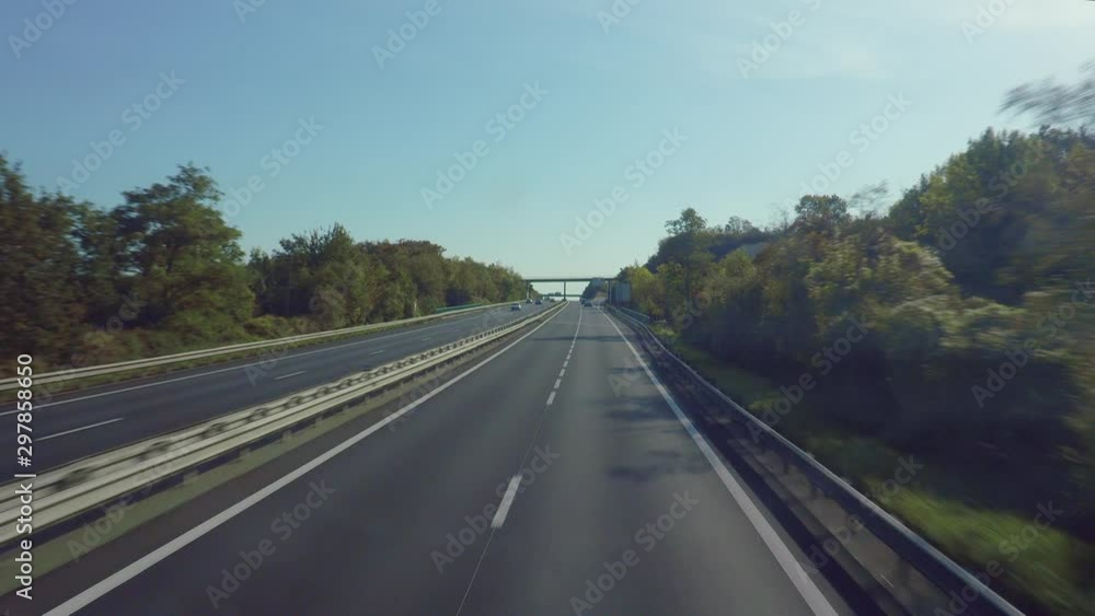 Fly over a highway covered with forest, passing the street signs and fast driven cars on both sides of the road, heading a bypass bridge. Fly over a highway covered with forest, passing the street signs and fast driven cars on both sides of the road, heading a bypass bridge.