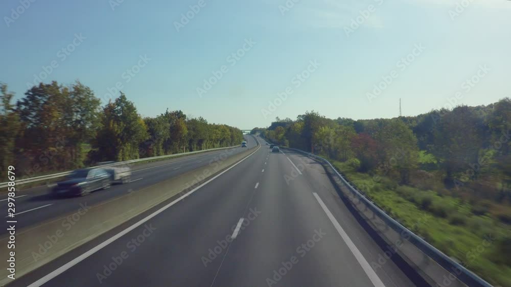 Fly over a highway covered with the greenery including trees and green fields, passing the fast driven cars on both sides of the road, Track view. Fly over a highway covered with the greenery including trees and green fields, passing the fast driven cars on both sides of the road, Track view.