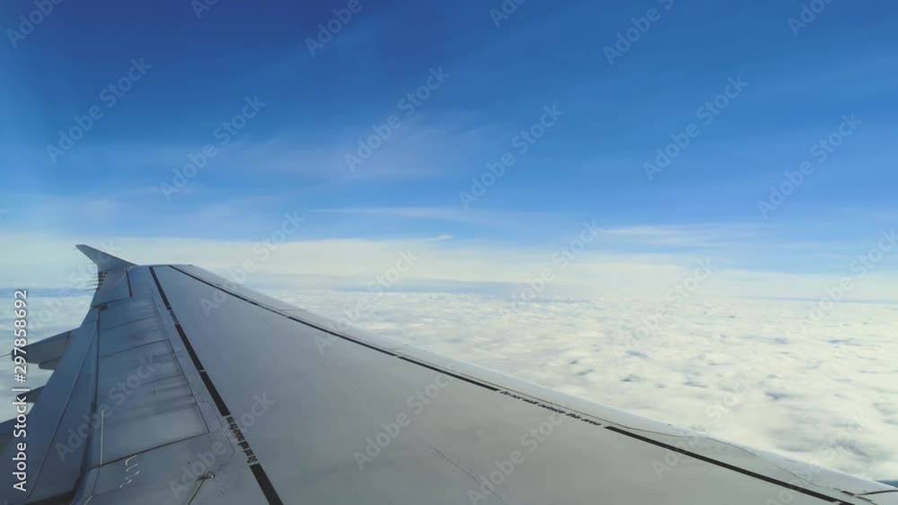 A smooth slow view of a Wing of an airplane flying above the clouds under the blue sky. A smooth slow view of a Wing of an airplane flying above the clouds under the blue sky.