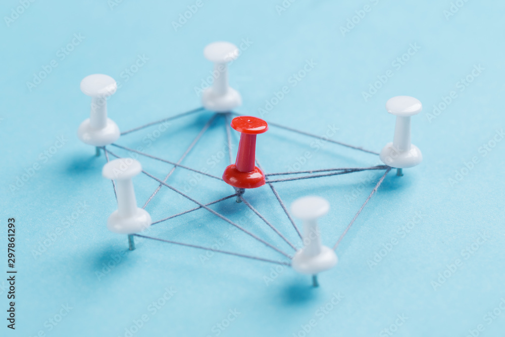 Obraz premium network with red and white pins and string, An arrangement of colorful pins linked together with string on a blue background suggesting a network of connections.