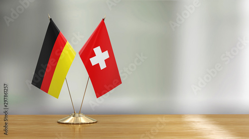 Swiss and German flag pair on a desk over defocused background  photo