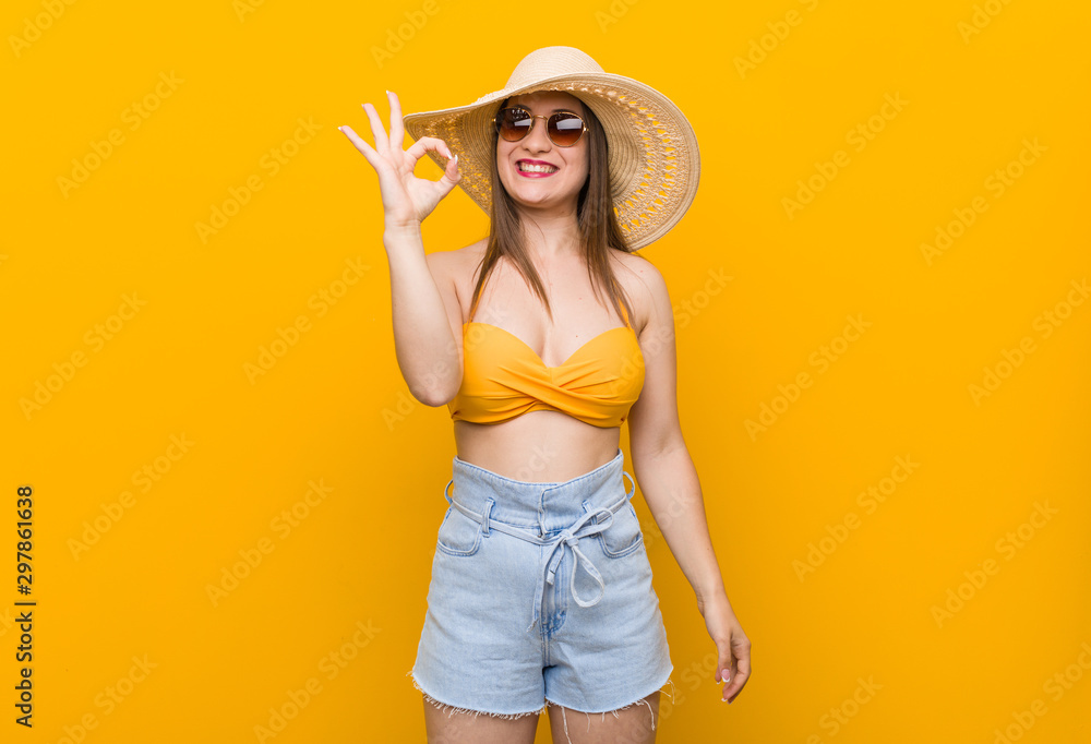 Young caucasian woman wearing a straw hat, summer look cheerful and confident showing ok gesture. Young caucasian woman wearing a straw hat, summer look cheerful and confident showing ok gesture.
