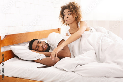 Distrustful black wife trying to check her husband cellphone in bed