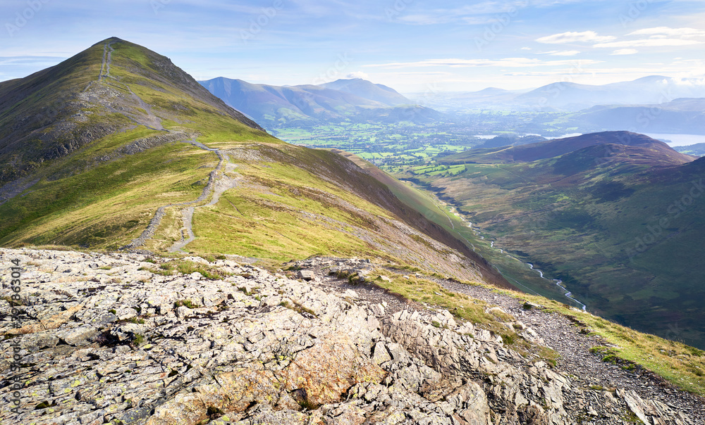 The rugged path from the summit of Hobcarton with Grisedale Pike in the distance and the valley of Coledale Beck far below, the Lake District, England, UK.