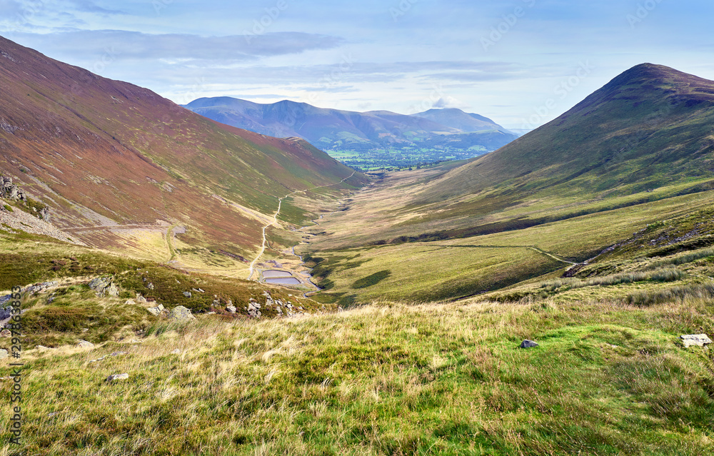 The valley of Coledale Beck with the summits of Outerside on the right and Skiddaw and Blencathra in the distance in the Lake District, England, UK.