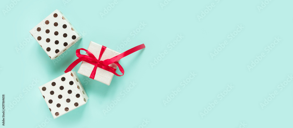 Christmas flat lay on top, New Year gift in a box with a red ribbon on a neo mint background, festive decor, copy space long banner