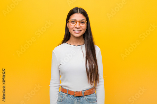 Foto Young pretty arab woman against a yellow background happy, smiling and cheerful
