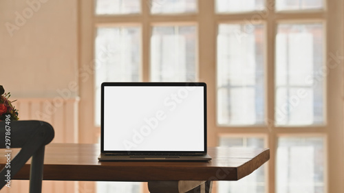 Mockup laptop computer on wooden table with chair in cafe. © Prathankarnpap
