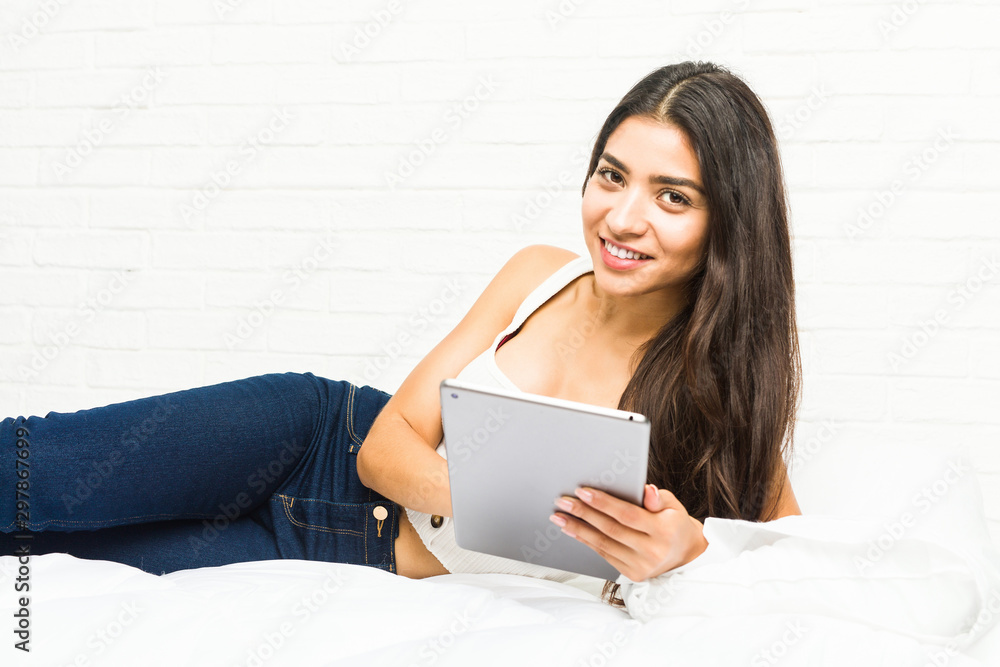 Young arab woman lying on the bed using a tablet Young arab woman lying on the bed using a tablet