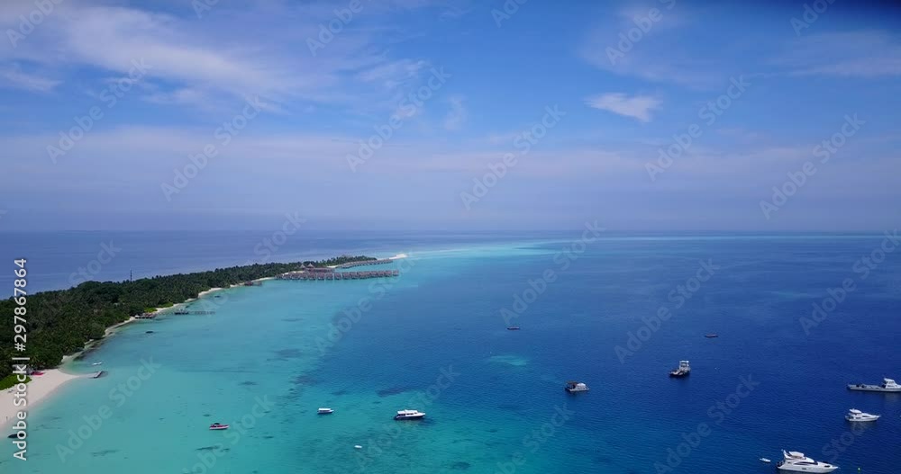 Lazily hovering over a tropical peninsula in Indonesia with resort housing and boats in the water Lazily hovering over a tropical peninsula in Indonesia with resort housing and boats in the water