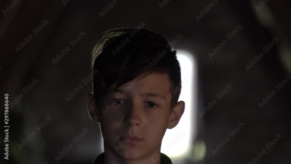 serious sad boy in a dark room looking at the camera serious sad boy in a dark room looking at the camera