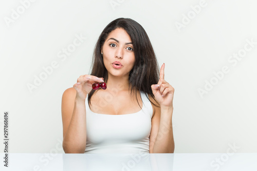 Young hispanic woman holding cherries having some great idea, concept of creativity.